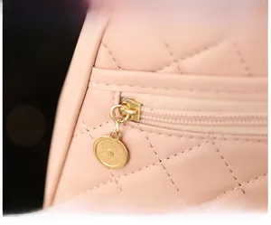 Close-up of pink quilted faux leather bag featuring smooth gold circular zipper hardware