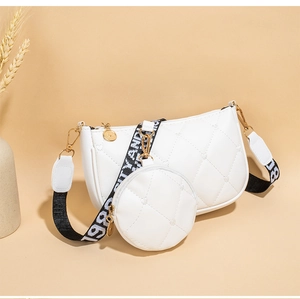 Détail de la broderie cœur sur sac matelassé blanc avec large bandoulière tissée