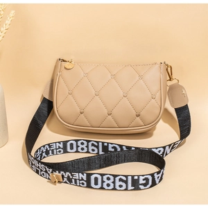 Détail du petit sac beige matelassé à cœurs avec large bandoulière graphique imprimée