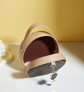 Detail view of khaki mini round bag featuring floral print, zip closure, and cat charm