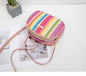 Detail of colorful woven shoulder bag with rainbow stripes and golden metal plaque