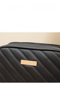Dettaglio borsa a mano nera trapuntata con cuciture diagonali e placca in metallo dorato
