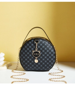 Detail of round black PU crossbody bag featuring clover pattern and gold cat charm