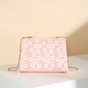 Pink Kelly bag with white floral lace embroidery and golden chain strap in studio setting