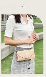 Outdoor shot of a woven crossbody bag with pink trim and a white butterfly accent