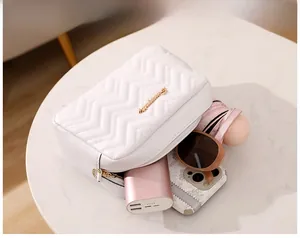 Detailed view of white quilted crossbody bag with gold logo and spacious interior storage