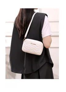 Detail of white quilted crossbody bag featuring elegant V-pattern and gold hardware