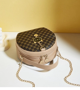 Close-up of small round crossbody bag featuring golden cat charm and dual zippers