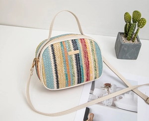 Close-up of colorful woven striped camera bag with gold hardware and ivory leather trim