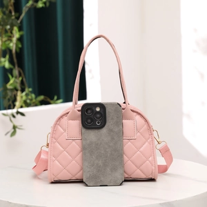 Pink quilted boston bag with top handles and adjustable strap next to a smartphone