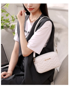 Macro view of white crossbody bag with wave quilted pattern and golden metal hardware