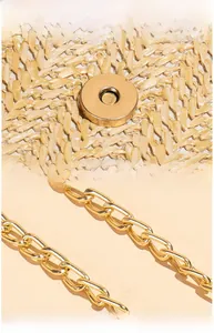 Detail of woven straw bag texture with high-polish gold magnetic closure and chain