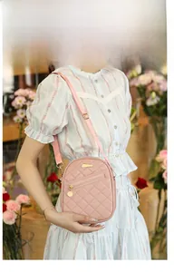 Pale pink quilted crossbody bag with adjustable strap worn by a model in floral dress
