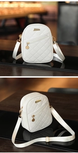 Detail of white quilted crossbody bag with golden hardware and adjustable fabric strap