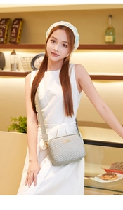Detail of chevron quilted camera bag with wide strap and golden hardware in lifestyle setting