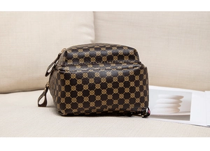 Detailed close-up of dark brown crossbody bag with clover patterns on a linen surface