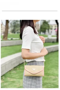 Detail of woven straw shoulder bag with pink leather trim and metal butterfly clasp
