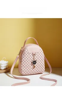 Detailed view of pink cat theme mini backpack with metal charm on yellow background