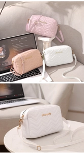 Detailed view of wave quilted crossbody camera bags with gold logo and premium hardware