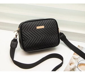 Detail view showing the V-shape quilted texture and gold hardware of the black crossbody bag