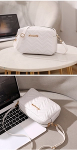 Detail of white chevron quilted crossbody bag with gold logo and dual zipper compartments