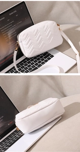 Detail of white camera bag featuring premium chevron quilted texture and gold hardware