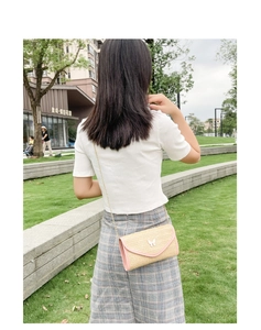 Outdoor shot showing the size and fit of a woven crossbody bag with butterfly detail