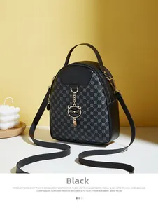 Detail of black mini leather backpack featuring cat pendant and geometric monogram pattern