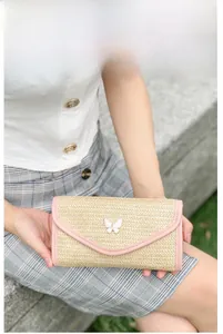 Detail of woven straw handbag with pink trim and white butterfly metal magnetic clasp