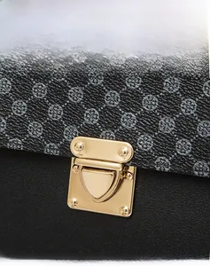 Vue macro du fermoir doré poli en forme de bouclier sur le sac en cuir à motifs