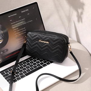 Classic black chevron quilted crossbody bag with gold logo on a laptop surface