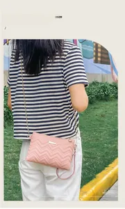 Detail view of pink PU leather crossbody bag featuring V-shaped quilting and gold chain