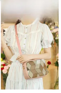 Close-up of a pink crossbody camera bag with geometric snake print panels and gold hardware