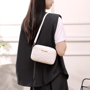 White quilted crossbody bag with wave texture and gold logo shown on model
