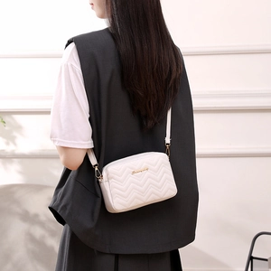 Elegant cream quilted wavy pattern shoulder bag with gold logo on a stylish model