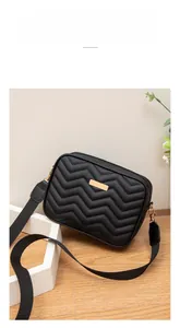 Detail of black chevron quilted crossbody bag with gold hardware and wide nylon strap