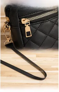 Detail of quilted leather camera bag featuring gold zippers and premium metal hardware
