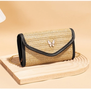 Detail of woven texture straw envelope bag with a white butterfly metal buckle