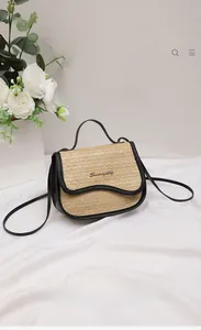 Detail of straw woven saddle bag with black trim and elegant metallic hardware