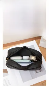 Detailed interior of a black leather camera bag showing storage for phone and cosmetics