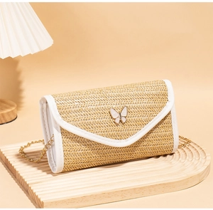 Detail of straw flap bag featuring a white butterfly metal lock and gold chain strap