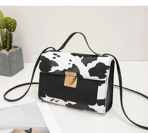 Détail du sac à bandoulière motif vache avec fermoir rotatif en métal doré en forme de cœur