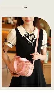 Pink quilted boston bag with adjustable strap worn by a model in a cafe setting