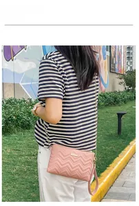 Outdoor model show featuring a pink wave-quilted crossbody bag with a gold chain strap