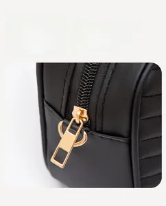 Close-up of premium gold metal zipper on black quilted leather crossbody bag