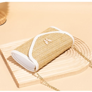 Close-up of woven straw bag with white butterfly clasp and gold chain detail