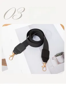 Detail of wide black woven bag strap with golden lobster clasps on magazine background