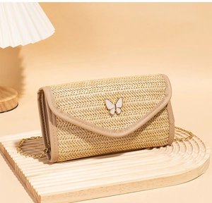 Detail showing beige woven texture and white butterfly metal clasp on the crossbody bag