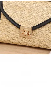 Detail of straw woven bag with black leather trim and polished gold metal clasp