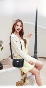Close-up of black chevron quilted crossbody bag with golden logo and wide strap